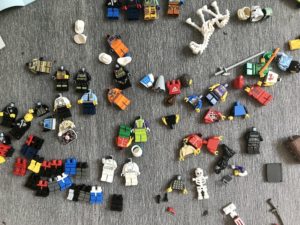 A dozen Lego Minifigure Legs, a Dozen Minifigure torsoes, a smattering of Lego helmets, a few Minifigures with no heads, a skeleton Lego horse, and a skeleton Lego minifigure with arms missing.